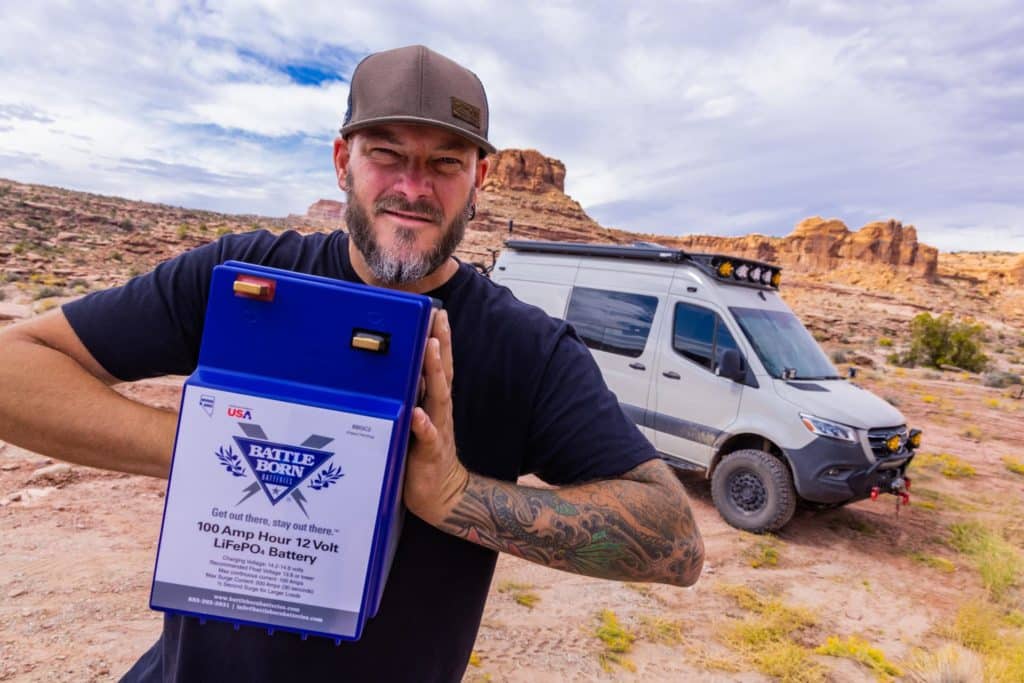 chad derosa holding lithium battery in front of overland van