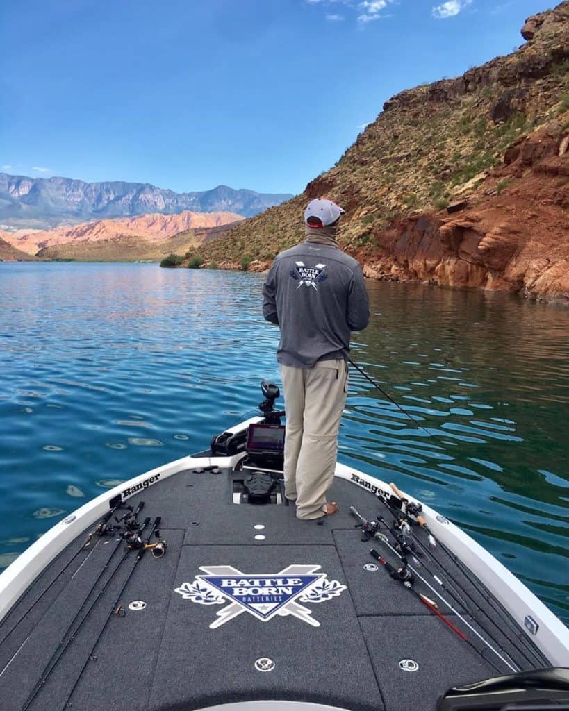 Darius Arberry fishing off the front of his bass boat while wearing a Battle Born Batteries long sleeve shirt