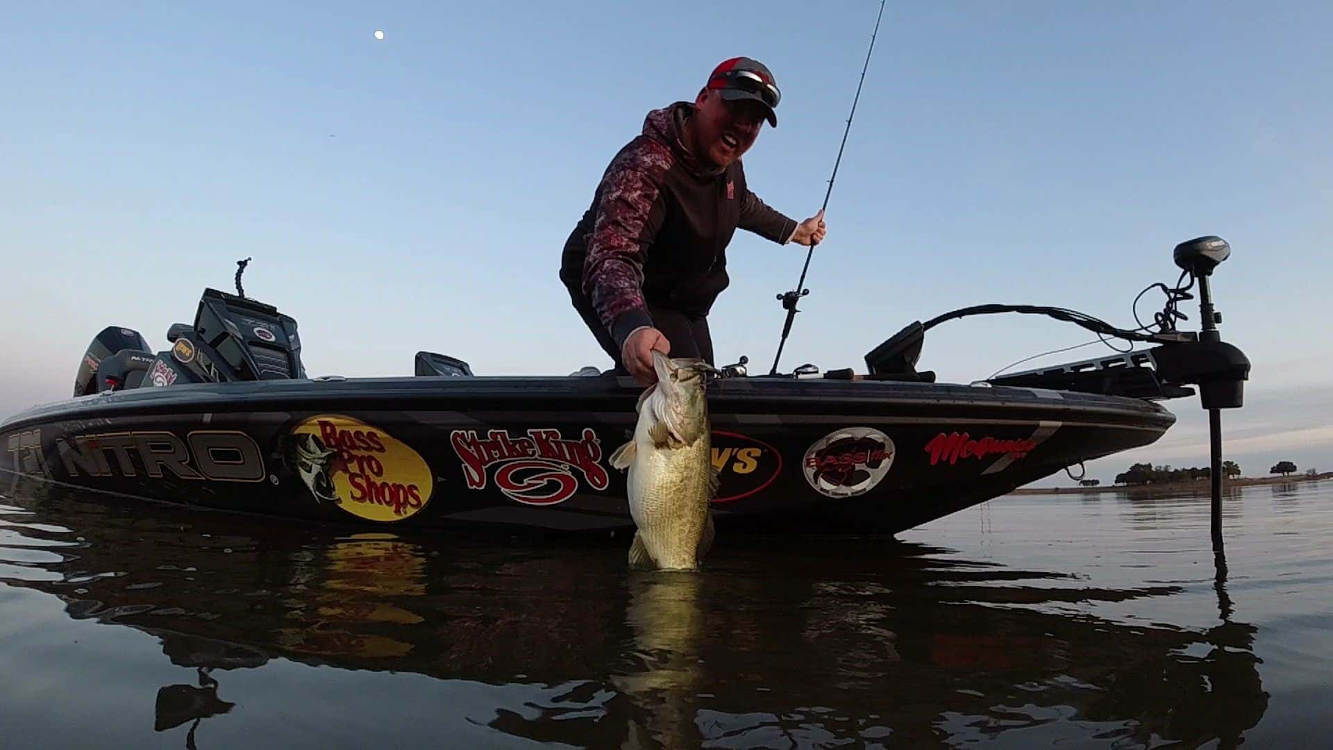 Man holding a large mouth bass off of his bass boat