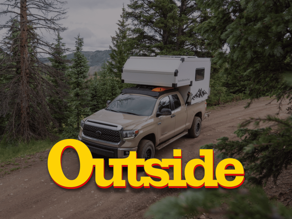 Outside Magazine Logo Over Truck Camper in the Forrest